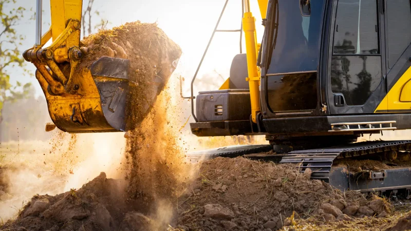 Close-up of excavator at construction site. Backhoe digging soil for earthwork and construction business. Excavating machine at work. Heavy machinery for earth moving and construction site development